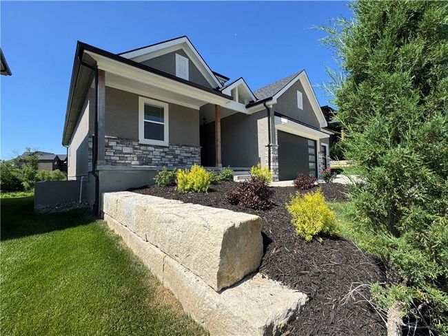 View of front facade with stucco siding, stone siding, an attached garage, and a front yard | Image 70