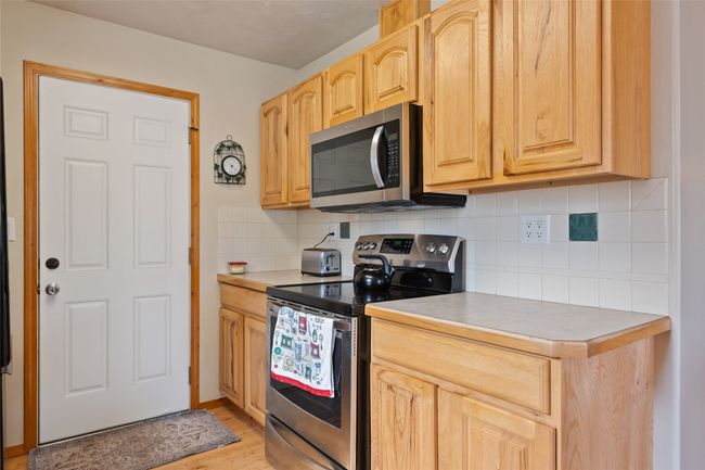 Kitchen with appliances with stainless steel finishes, decorative backsplash, light wood-style floors, and light countertops | Image 28