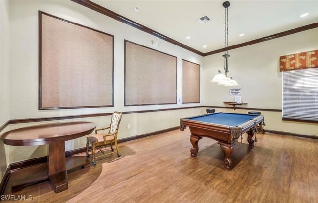 Recreation room with wood finished floors, crown molding, baseboards, and visible vents | Image 25