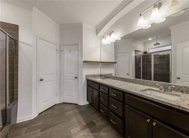 Bathroom featuring vanity, ornamental molding, and a shower with door | Image 26