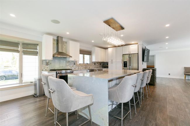 Kitchen with baseboards, wall chimney exhaust hood, appliances with stainless steel finishes, and crown molding | Image 9