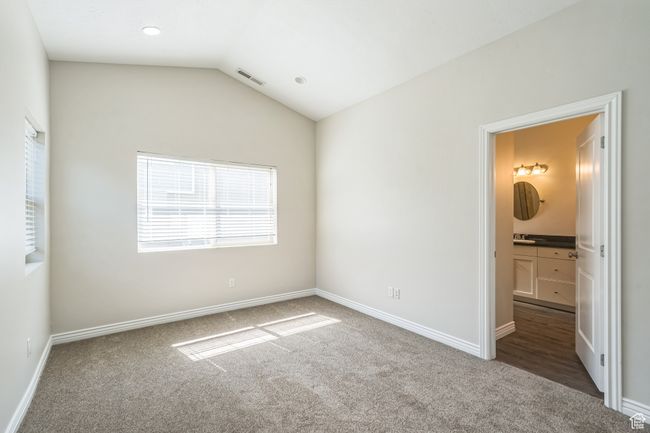 Unfurnished bedroom featuring carpet floors, lofted ceiling, and connected bathroom | Image 30