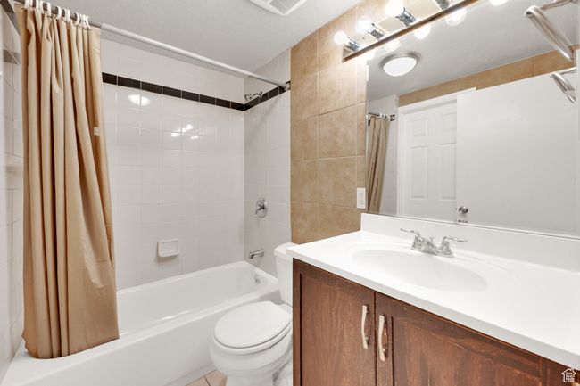 Full bathroom with shower / bath combination with curtain, vanity, and toilet | Image 22