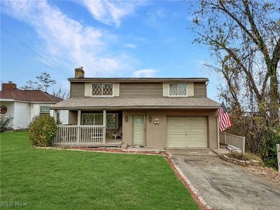 View of front facade featuring covered porch, a front yard, and a garage | Image 1