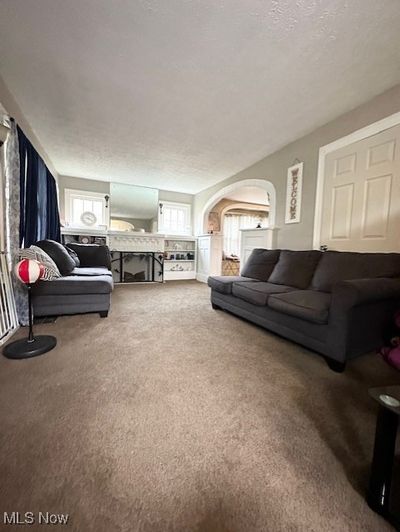 Carpeted living room with a textured ceiling and a fireplace | Image 2