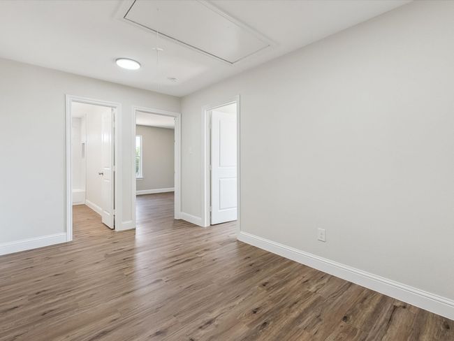 Spare room with attic access, baseboards, and wood finished floors | Image 17