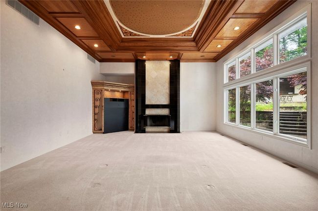 Unfurnished living room featuring crown molding, healthy amount of natural light, carpet flooring, a fireplace, and recessed lighting | Image 12