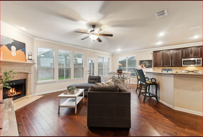 Living area featuring a ceiling fan, dark wood-style flooring, a fireplace, ornamental molding, and recessed lighting | Image 12