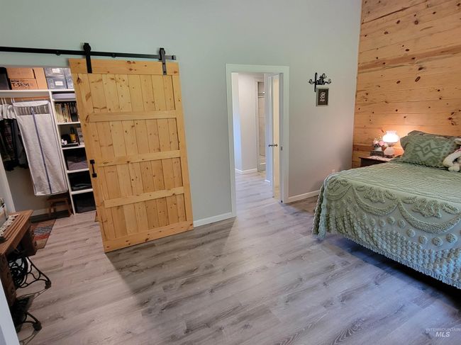 Bedroom featuring wood finished floors, wood walls, a barn door, and a high ceiling | Image 17