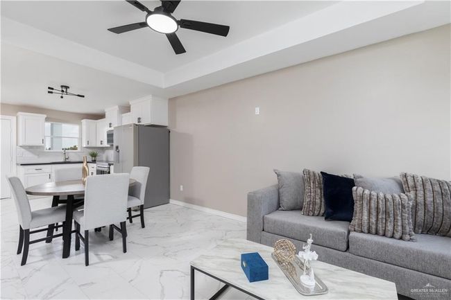 Living room featuring ceiling fan, light marble finish floors, and baseboards | Image 5