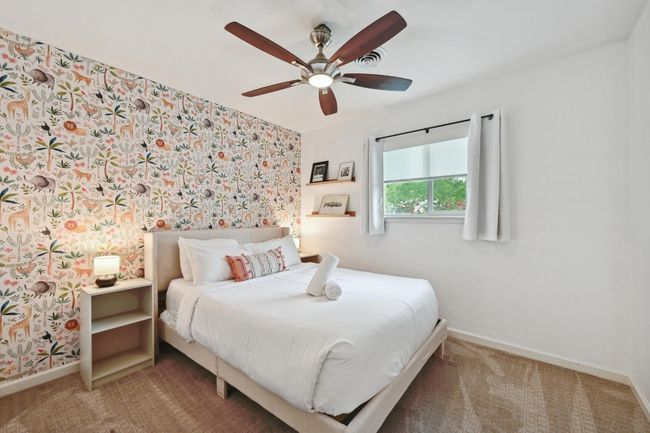 This charming secondary bedroom boasts an accent wall with designer wallpaper. | Image 28