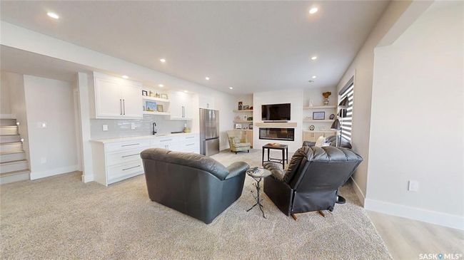 Living room featuring bar with sink, recessed lighting, stairs, and a glass covered fireplace | Image 30