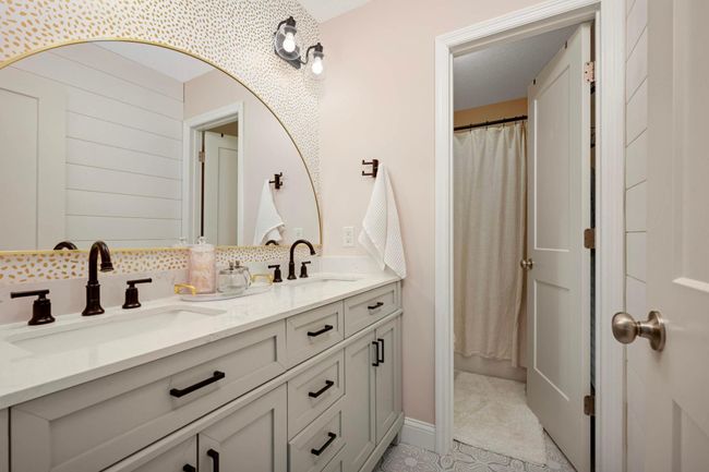 Upper-level full bathroom with separate vanity area. This bathroom has been updated with a new vanity, shiplap wall, trendy flooring, mirror, and wall coverings. | Image 34