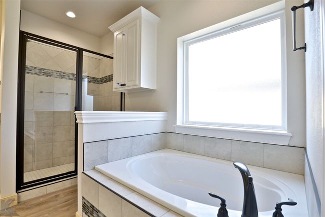 Bathroom featuring a garden tub, a shower stall, wood finished floors, and recessed lighting | Image 16