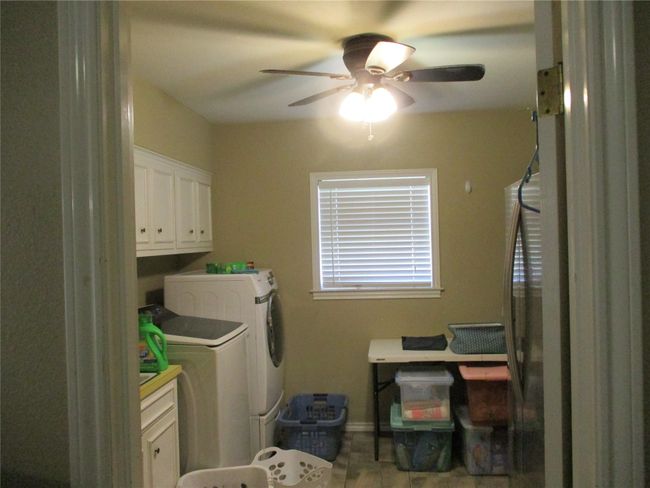 Laundry area with tile patterned floors, washer and clothes dryer, cabinets, and ceiling fan | Image 15