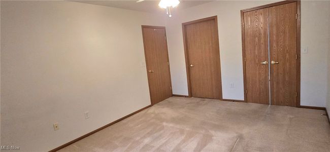 Unfurnished bedroom with light colored carpet, two closets, baseboards, and ceiling fan | Image 16