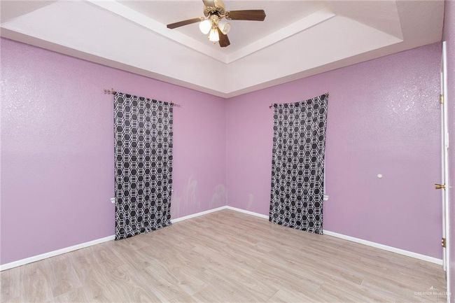 Spare room with a raised ceiling, ceiling fan, and wood finished floors | Image 15