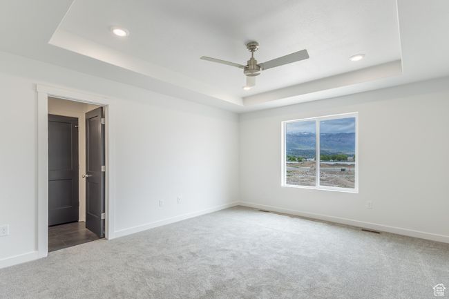 Carpeted spare room with a tray ceiling, ceiling fan, baseboards, and recessed lighting | Image 8