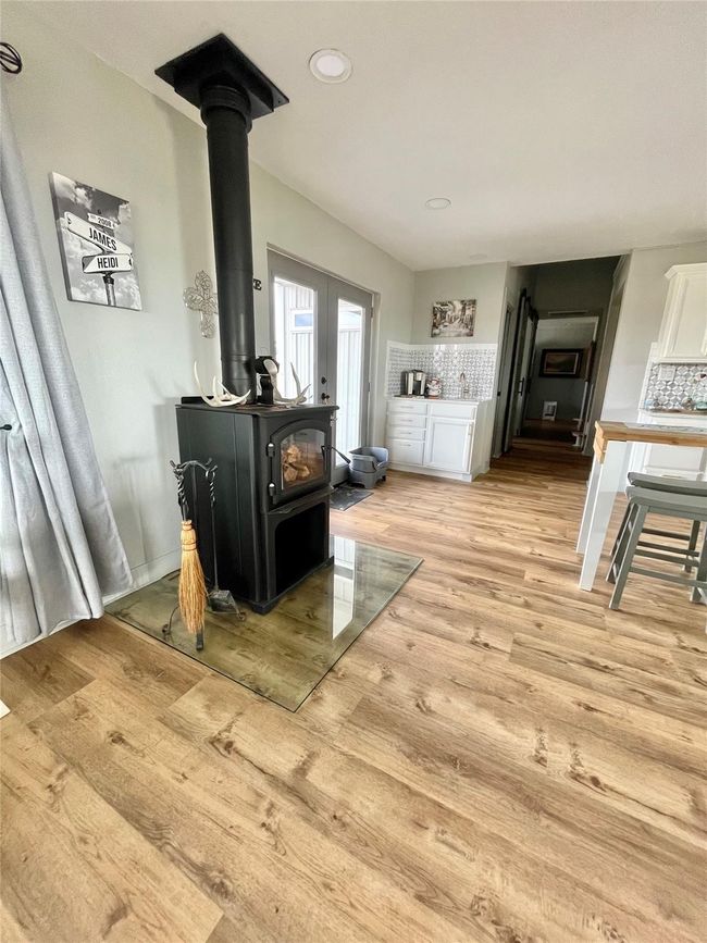 Detailed view of a wood stove, decorative backsplash, wood finished floors, and recessed lighting | Image 7
