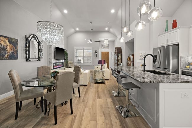 Dining area featuring vaulted ceiling, a chandelier, light wood-type flooring, recessed lighting, and a ceiling fan | Image 5