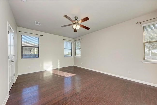 Bedroom featuring a ceiling fan, wood finished floors, healthy amount of natural light, and baseboards | Image 9