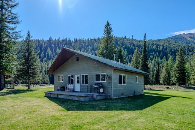 View of front facade featuring a wooded view, a front lawn, a patio area, a mountain view, and metal roof | Image 36