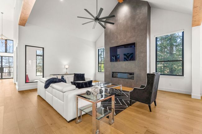 Living area with ceiling fan with notable chandelier, high vaulted ceiling, beamed ceiling, light wood-style flooring, and a fireplace | Image 5