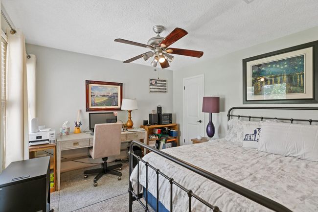 This versatile secondary bedroom offers flexible living space with room for both sleeping and work areas, featuring neutral paint, ceiling fan, ample natural light, and a walk-in closet, making it perfect for a guest room, home office, or kids room. | Image 22
