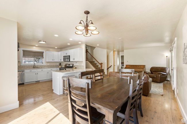 Dining area featuring stairway, light wood-type flooring, baseboards, a notable chandelier, and recessed lighting | Image 13