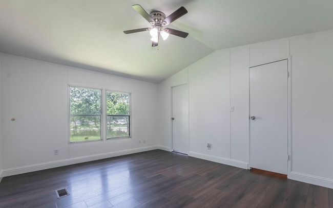 Unfurnished bedroom featuring vaulted ceiling, dark wood-style flooring, and a ceiling fan | Image 8