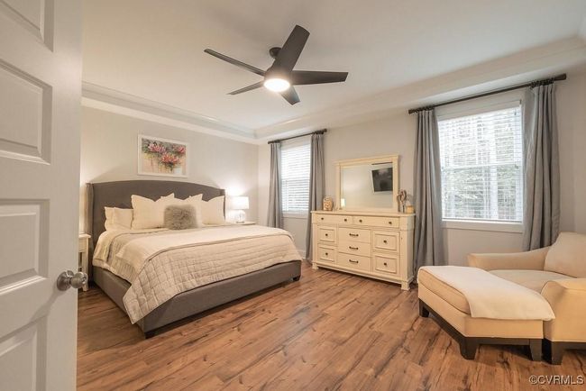 Bedroom with wood finished floors, multiple windows, a ceiling fan, and ornamental molding | Image 14