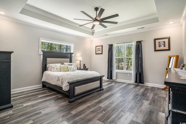 Bedroom featuring a raised ceiling, dark wood-type flooring, ornamental molding, baseboards, and ceiling fan | Image 23