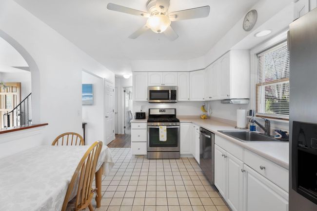 Kitchen with white cabinetry, appliances with stainless steel finishes, sink, and ceiling fan | Image 7