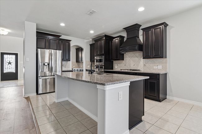 Kitchen featuring visible vents, arched walkways, custom exhaust hood, stainless steel appliances, and a sink | Image 11