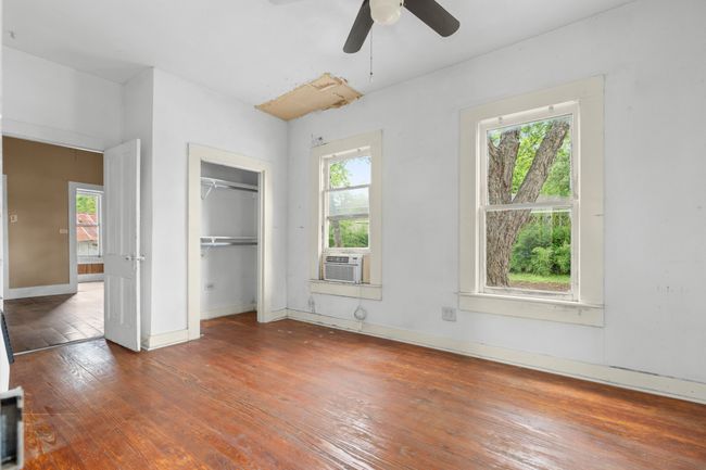 Unfurnished bedroom featuring wood-type flooring, baseboards, cooling unit, a closet, and a ceiling fan | Image 15
