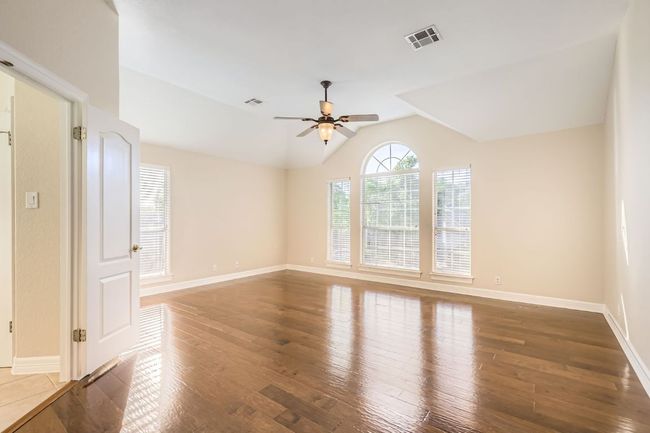 Spare room with wood finished floors, ceiling fan, lofted ceiling, and visible vents | Image 22