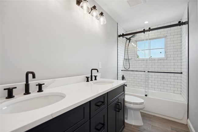 Bathroom with bath / shower combo with glass door, wood finished floors, and double vanity | Image 20