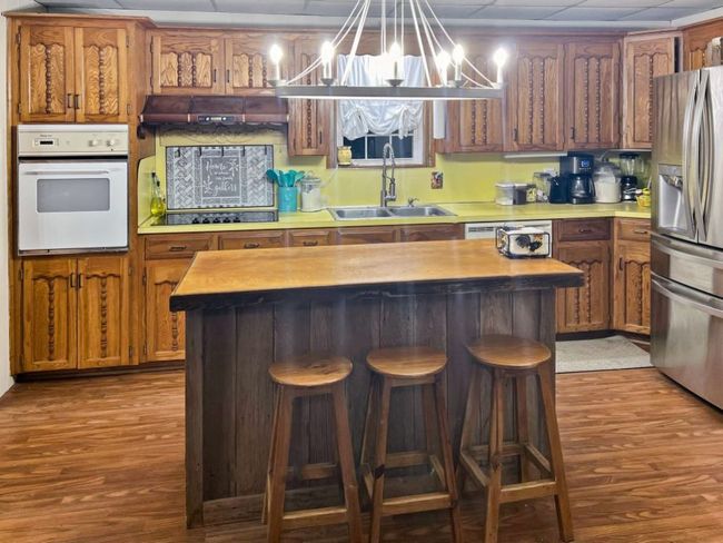 Kitchen featuring a sink, dark wood-type flooring, stainless steel refrigerator with ice dispenser, white oven, and black electric stovetop | Image 4