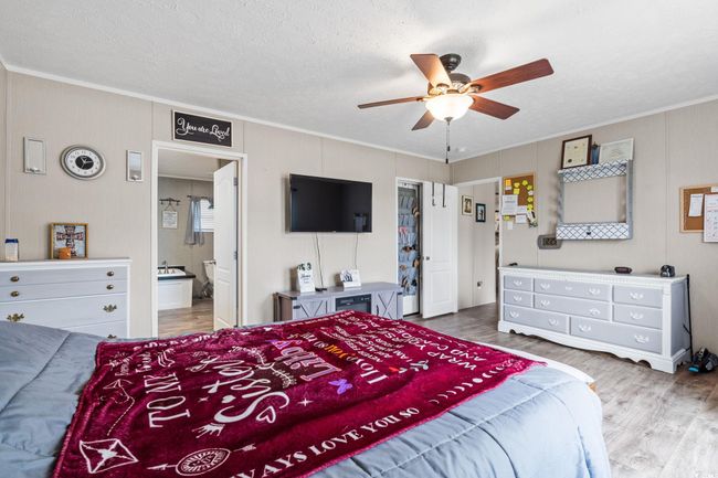 Bedroom with ornamental molding, wood finished floors, ceiling fan, ensuite bathroom, and a textured ceiling | Image 16