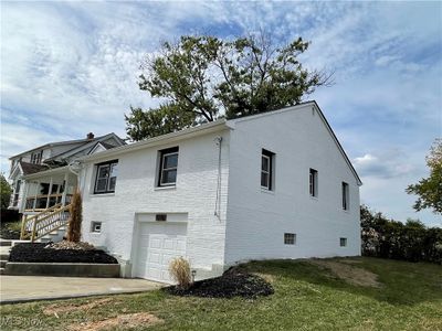 View of side of home with a lawn and a garage | Image 2