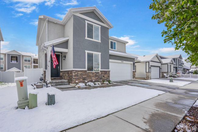View of front of home with stone siding, concrete driveway, fence, a garage, and stucco siding | Image 32