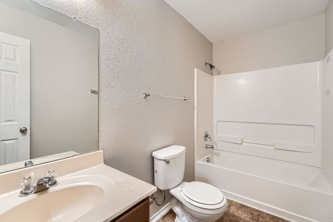 Full bath featuring vanity, toilet, shower / washtub combination, tile patterned floors, and a textured wall | Image 9