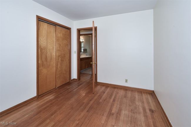 Unfurnished bedroom with baseboards, wood finished floors, and a closet | Image 32
