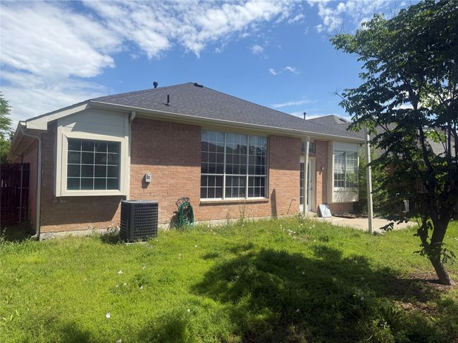 Rear view of house with fence, a lawn, brick siding, and central AC | Image 19