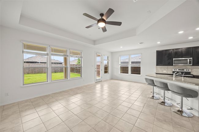 Living area with a raised ceiling, recessed lighting, a ceiling fan, light tile patterned flooring, and baseboards | Image 6