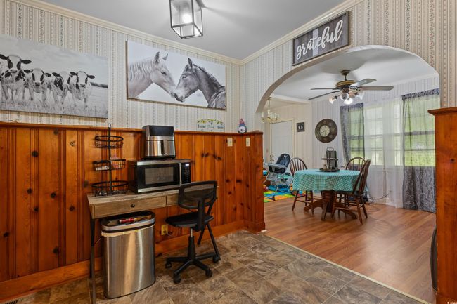 Home office with wallpapered walls, crown molding, a ceiling fan, and arched walkways | Image 19