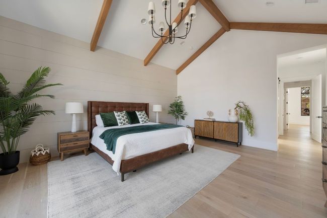 Bedroom featuring light wood finished floors, visible vents, an inviting chandelier, high vaulted ceiling, and beam ceiling | Image 16