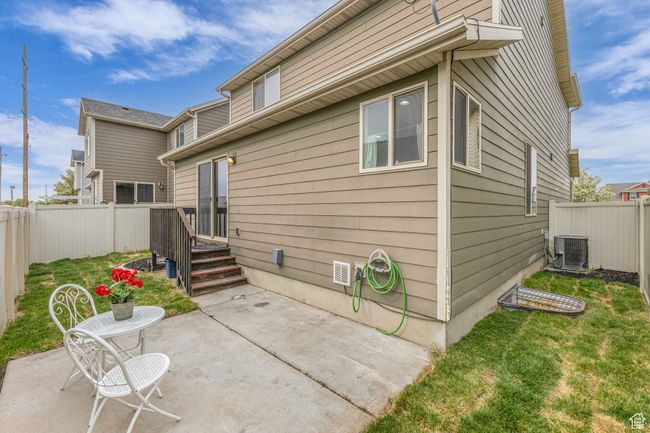 Rear view of property featuring a yard, a fenced backyard, a patio, and central AC unit | Image 22