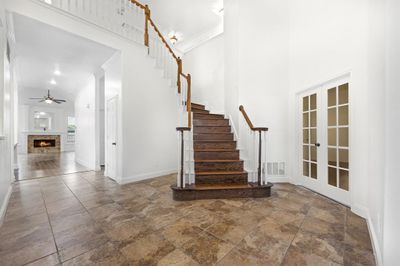 Stairs with a high ceiling, french doors, ceiling fan, and crown molding | Image 2