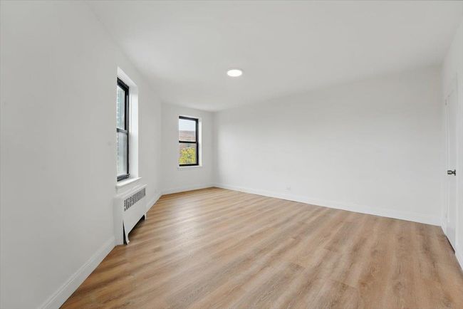 Spare room featuring radiator, light wood-style floors, and baseboards | Image 16